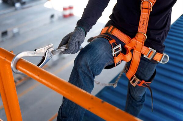 Worker in safety harness securing a rope on a building exterior.