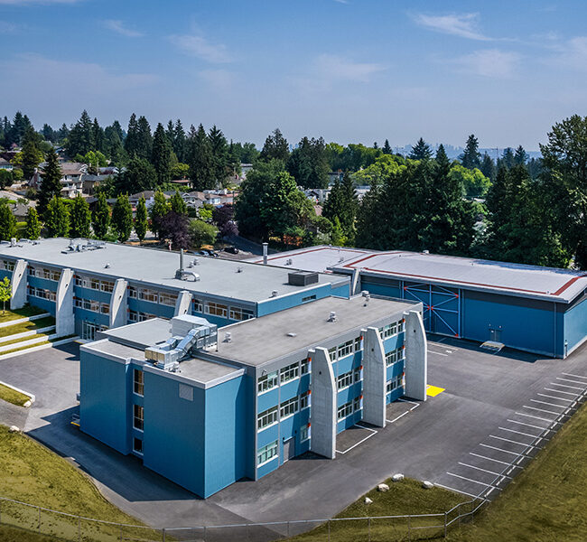 Aerial view of a blue school building with a playground and trees around.