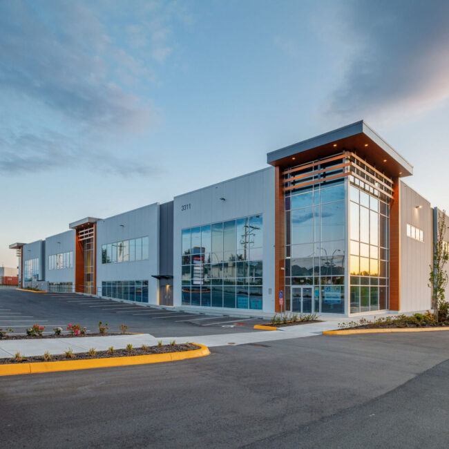Modern commercial building with large glass windows during sunset.