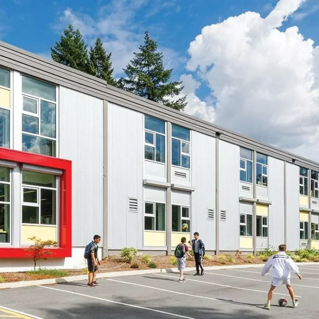 Children playing outside a modern school building on a sunny day.